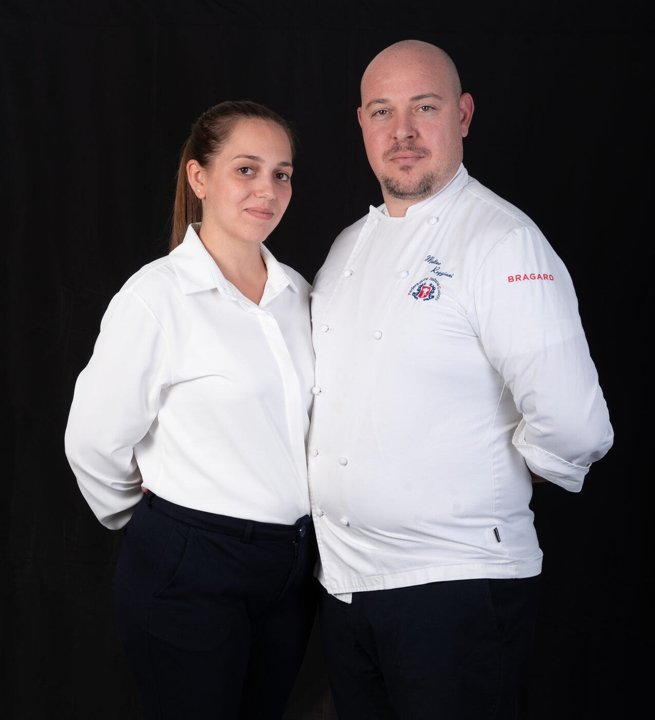 Nadia e Matteo Reggiani in giacca bianca su fondo nero